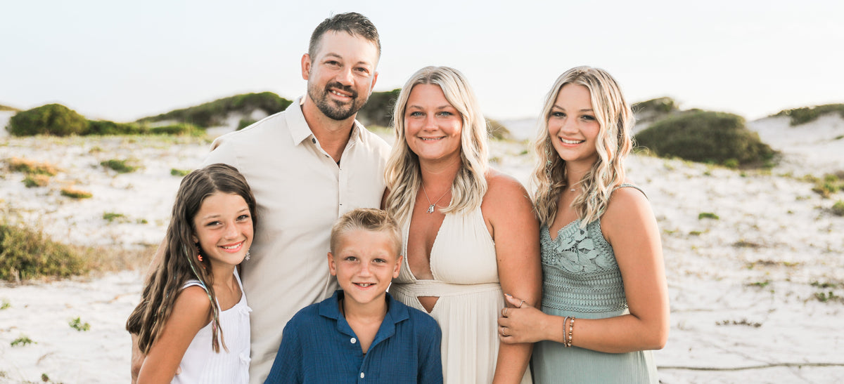 Family of five posing on a sandy beach